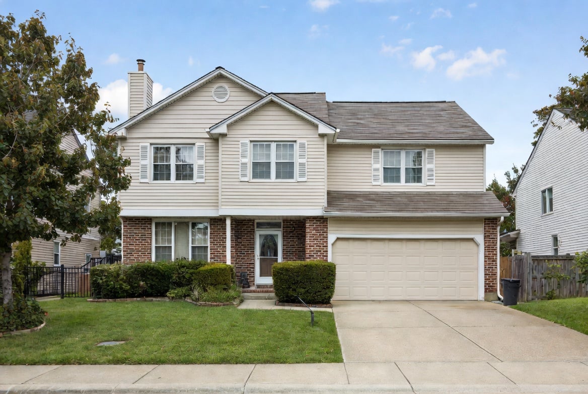 Two-story beige house with brick accents, white shutters, and a two-car garage on a quiet suburban street | TruAssign