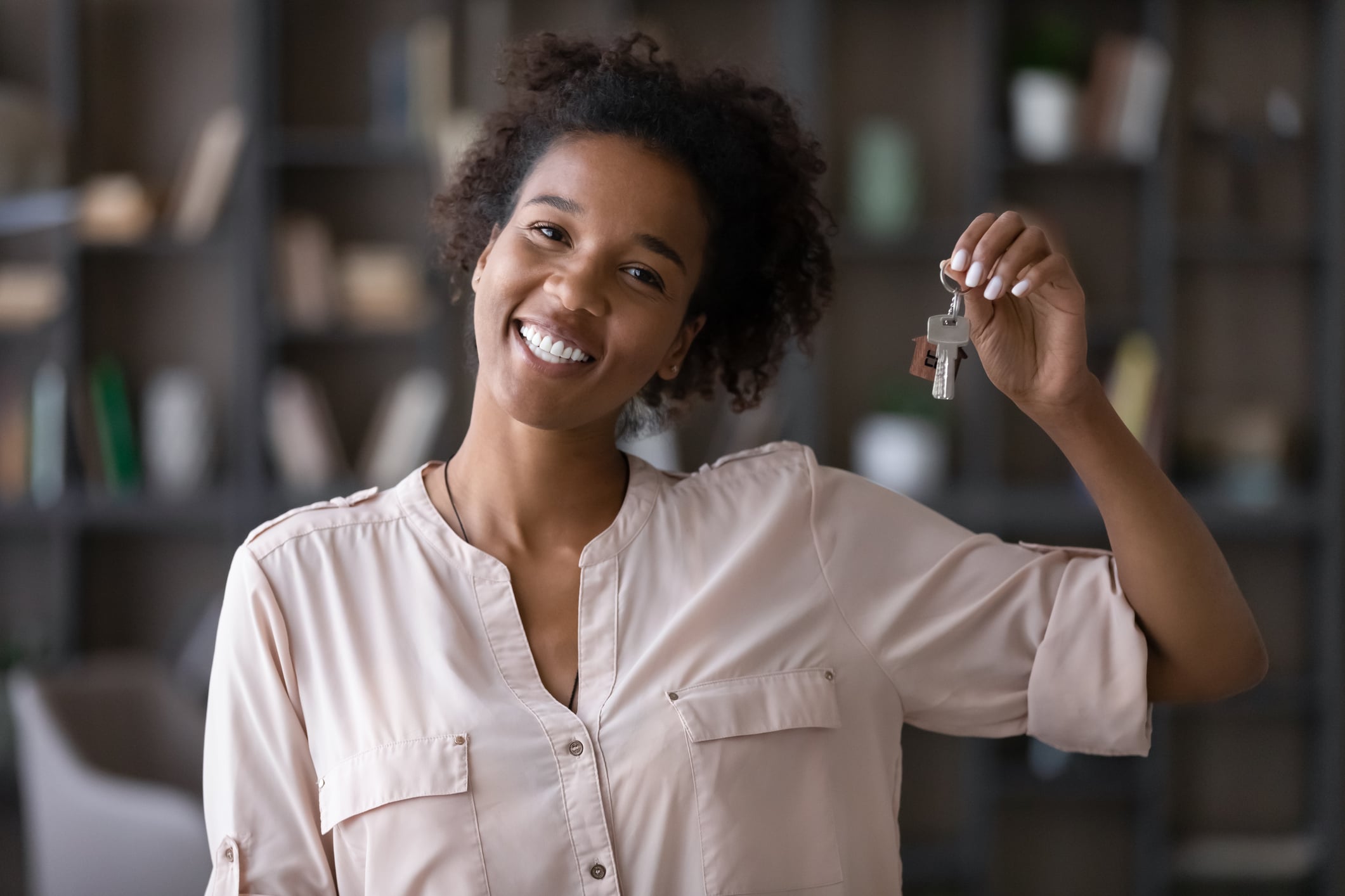 Smiling woman holding house keys after selling her home for cash | TruAssign